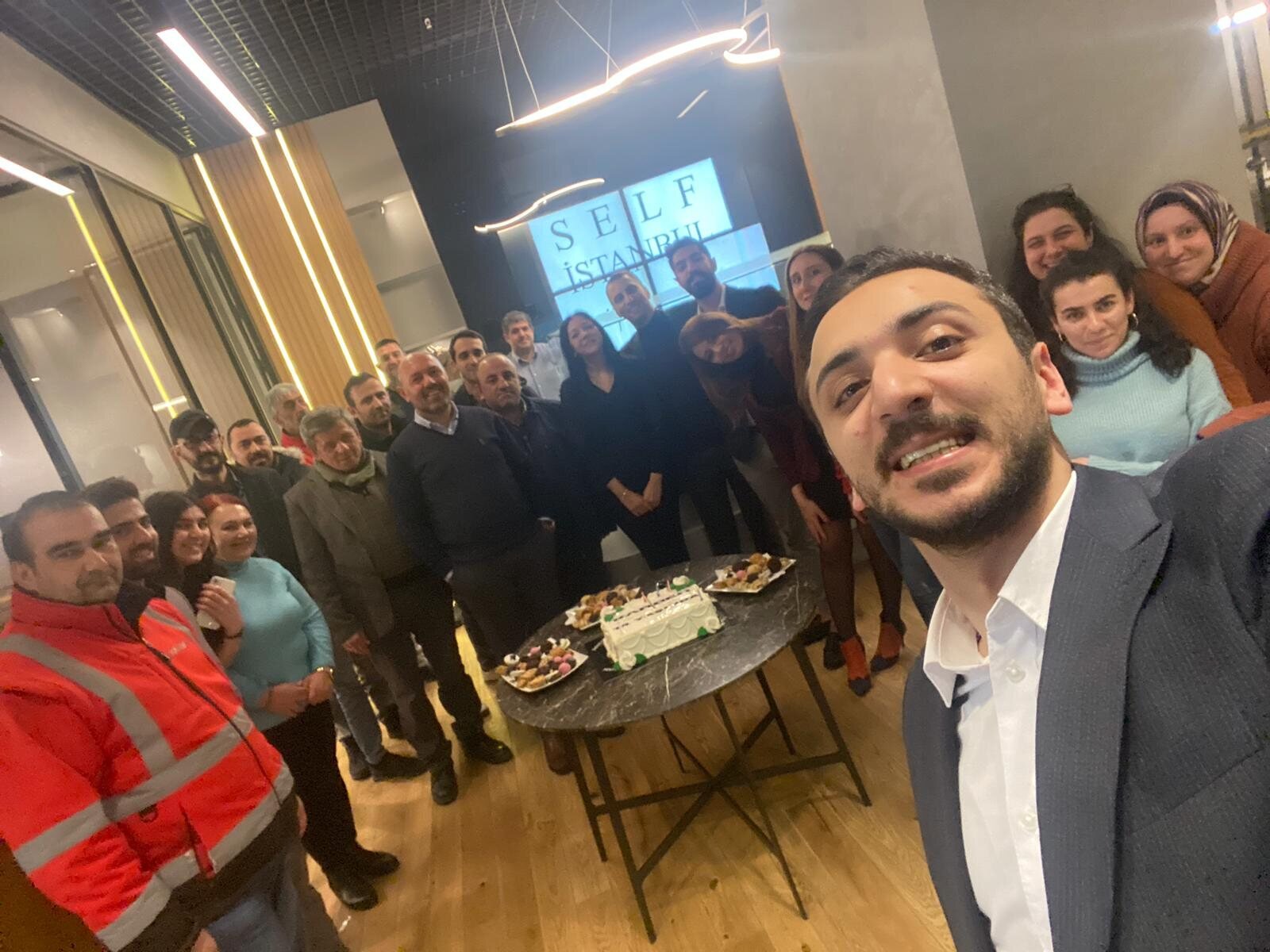 أحمد في صورة سيلفي مع فريق شركة الإنشاء العقاري، في عيد ميلاد الشركة